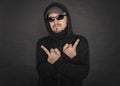 Man in the black hoody with hood wearing sunglasses showing middle fingers