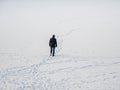 A man in a black jacket with a backpack walking on snow, footprints in snow, behind Royalty Free Stock Photo