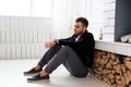 A man in black jacket resting near fireplace. Royalty Free Stock Photo