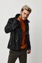 man in black leather jacket and orange sweater blond light background cropped view Royalty Free Stock Photo