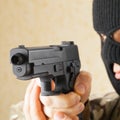 Man in black mask holding gun before him - studio shot