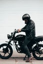 Man with a black motorcycle against a white garage door. Royalty Free Stock Photo