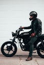 Man with a black motorcycle against a white garage door. Royalty Free Stock Photo