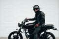 Man with a black motorcycle against a white garage door. Royalty Free Stock Photo