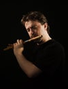 Man in black plays a flute Royalty Free Stock Photo