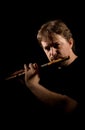 Man in black plays a flute Royalty Free Stock Photo