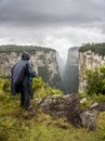 Man in black raincoat and hood standing on the edge of a cliff before rain, canyon itambezinho Royalty Free Stock Photo