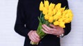 A man in a black shirt holds a bouquet of yellow tulips on a white background Royalty Free Stock Photo