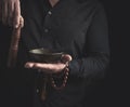 Man in a black shirt rotates a wooden stick around a copper Tibetan bowl of water. ritual of meditation Royalty Free Stock Photo