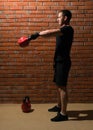 Man in black sportswear is engaged with a kettlebell of sports against the backdrop of a brick wall Royalty Free Stock Photo