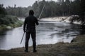 A man in black stands holding a katana in his hand with his back to the camera in the rain in the forest on the edge of Royalty Free Stock Photo