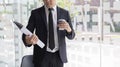 Man in a black suit holds a folder and a coffee mug, young Asian businessman Royalty Free Stock Photo