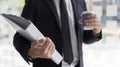 Man in a black suit holds a folder and a coffee mug, young Asian businessman Royalty Free Stock Photo