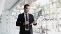 Man in a black suit holds a folder and a coffee mug, young Asian businessman stands Royalty Free Stock Photo