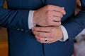 A man in a black suit straightens his cufflinks