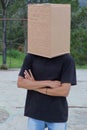 A man in a black t-shirt with a cardboard box on his head standing in the park Royalty Free Stock Photo