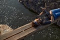 a man in a black T-shirt lies on a wooden bridge over a mountain river Royalty Free Stock Photo