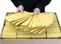 Man in a black technical shirt spreading a pile of padded envelopes over a cardboard shipping box full of yellow bubble mailers Royalty Free Stock Photo