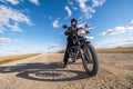 Man in a black uniform on bike against the backdrop of panorama of field and blue sky. motorcycle travel concept Royalty Free Stock Photo