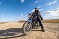 Man in a black uniform on bike against the backdrop of panorama of field and blue sky. motorcycle travel concept Royalty Free Stock Photo