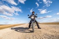Man in a black uniform on bike against the backdrop of panorama of field and blue sky. motorcycle travel concept Royalty Free Stock Photo