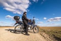 Man in a black uniform on bike against the backdrop of panorama of field and blue sky. motorcycle travel concept Royalty Free Stock Photo