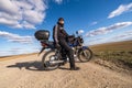 Man in a black uniform on bike against the backdrop of panorama of field and blue sky. motorcycle travel concept Royalty Free Stock Photo