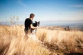 Man Sitiing With His Dog On Mountain Meadow. Black And White Border Collie In High Golden Grass