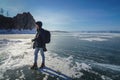 Man in black winter jacket solo travel in frozen lake Baikal with camera