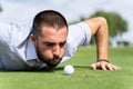 Man blowing a golf ball into a hole Royalty Free Stock Photo