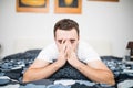 Man blowing his nose while lying sick in bed at home Royalty Free Stock Photo