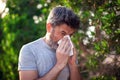 Man blowing nose in front of blooming tree. Spring allergy concept Royalty Free Stock Photo