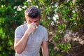 Man blowing nose in front of blooming tree. Spring allergy concept Royalty Free Stock Photo