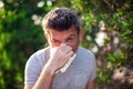 Man blowing nose in front of blooming tree. Spring allergy concept Royalty Free Stock Photo