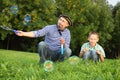 Man is blowing soap bubbles, his son is looking