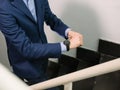 Man in blue blazer jacket walking upstairs checking the time on his watch Royalty Free Stock Photo