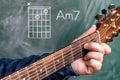 Man playing guitar chords displayed on a blackboard, Chord A minor 7