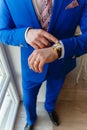 Man in a blue expensive suit and vest looks at expensive watches. closeup designer watch on businessman hand, he looks on the time Royalty Free Stock Photo