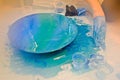 A man in a blue glove beautifully paints draws an acrylic blue multi-colored resin a round home-made board