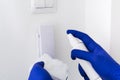 Man in blue gloves cleaning door phone with sanitizer