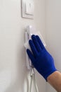 Man in blue gloves cleaning with tissue intercome or door phone in flat