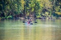 Man and blue heeler dog floating-paddling river together on paddleboard with bokeh forest in background - tranquil scene