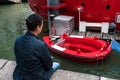 Man in blue jacket looking at Red Hot Tag with melted stove in Rotterdam. The hot tub concept in a floating wood-fired