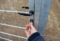 Man in a blue jacket opens with a key a gate to the garden, a paddock for tigers, bears, dogs, forest fencing highway fence. galva Royalty Free Stock Photo