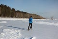 Man in a blue jacket running across the ice of a frozen river, O