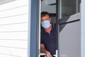 Man in blue medical face mask on home door protect coronavirus house in quarantine Royalty Free Stock Photo