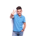 Man in blue polo shirt showing the victory sign