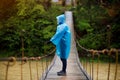 Man in blue raincoat walking in coniferous forest during rainy foggy day Royalty Free Stock Photo