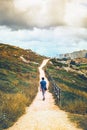 Adult man climbing the hill on a dirt road between vegetation and wooden railings with the city of acoruna in the background Royalty Free Stock Photo