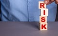 A man in a blue shirt composes the word RISK from wooden cubes vertically